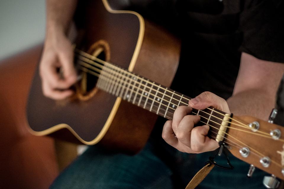 Les mains d'un guitariste sur une guitare en bois sombre