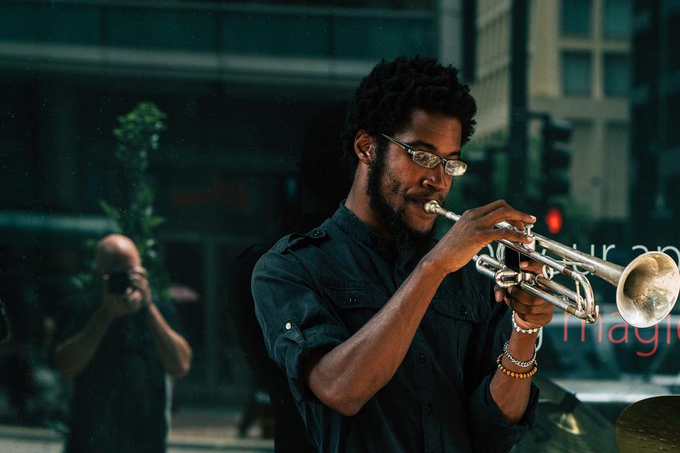 Un joueur de trompette. On aperçoit le reflet du photographe dans une vitre.